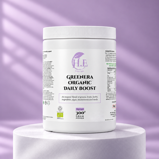A white plastic tub of H.E Pure Greenera Organic Daily Boost powder, 300g, displayed on a white cylindrical pedestal against a lavender-purple background with soft diagonal shadows.