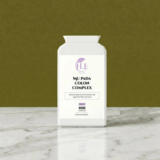 A white bottle of H.E Wellness Center Mu Pada Colon Complex dietary supplement, set on a white marble surface against a textured olive green background.