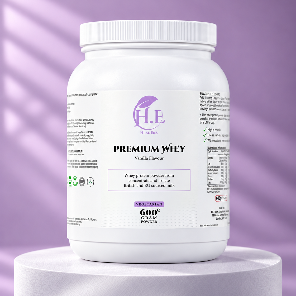 A white plastic tub of H.E Wellness Premium Whey Vanilla Flavour powder, displayed on a white cylindrical pedestal against a lavender-purple background with soft diagonal shadows.