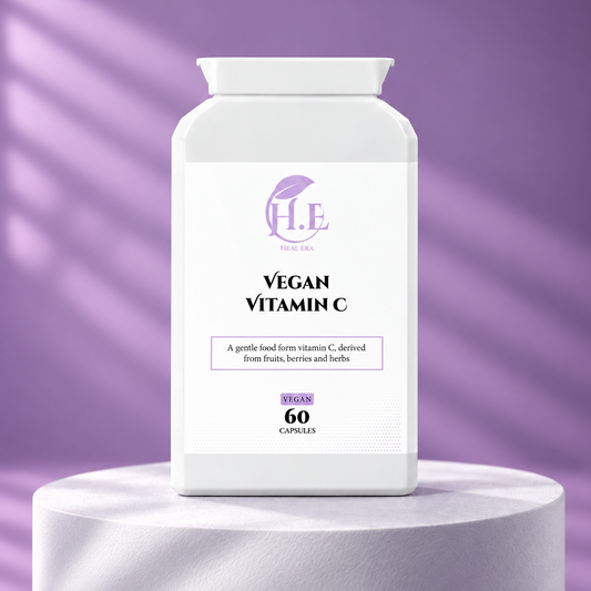 A white bottle of Vegan Vitamin C capsules by H.E Wellness Labs, displayed on a white cylindrical pedestal against a purple background with soft diagonal shadows.